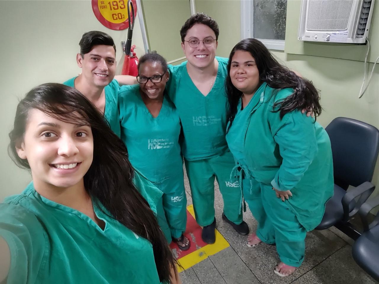 Selfie de Camila Cardoso, de jaleco, com quatro colegas de plantão no hospital