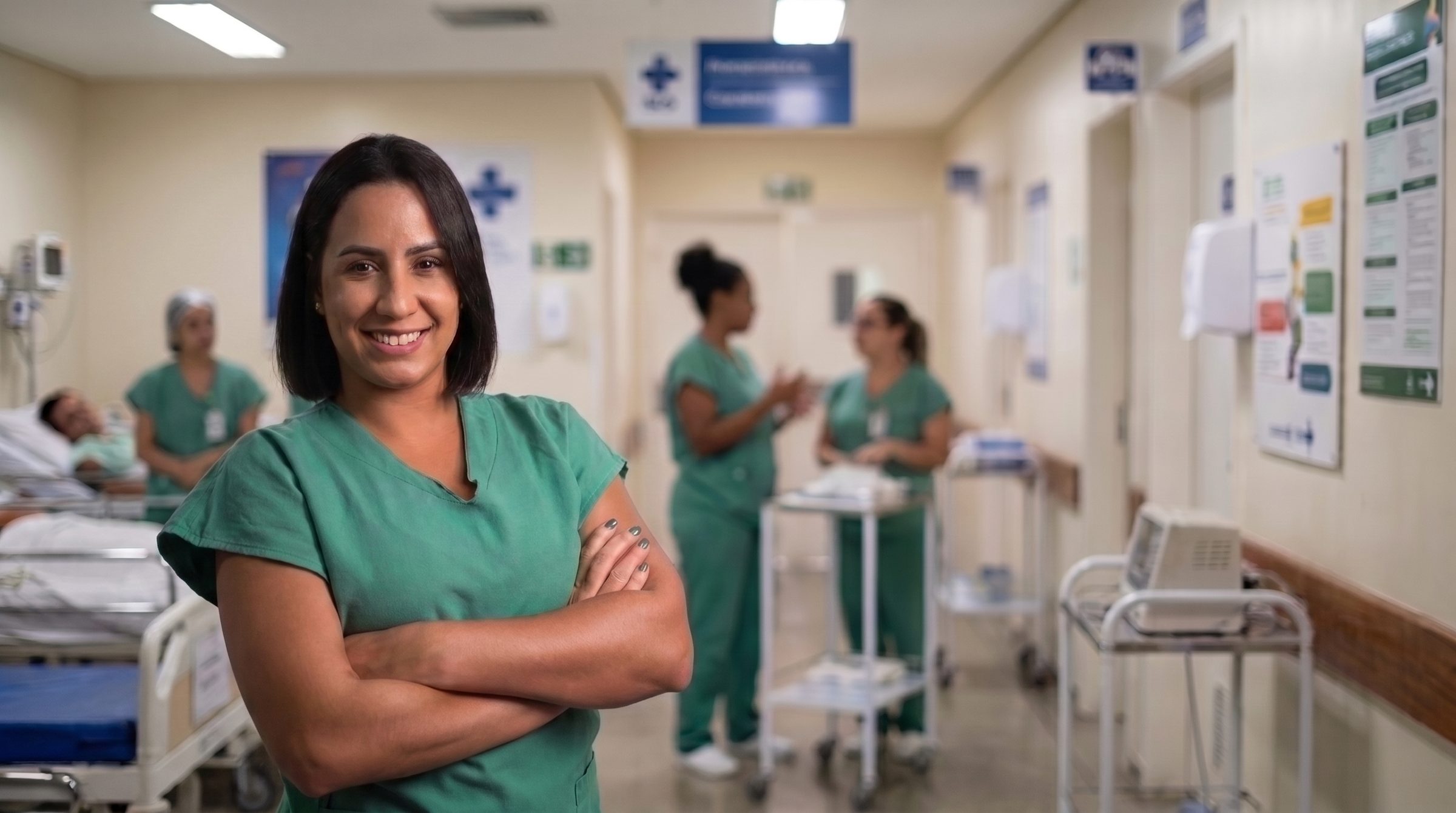Camila Cardoso, técnica de enfermagem, no corredor do hospital com a equipe ao fundo