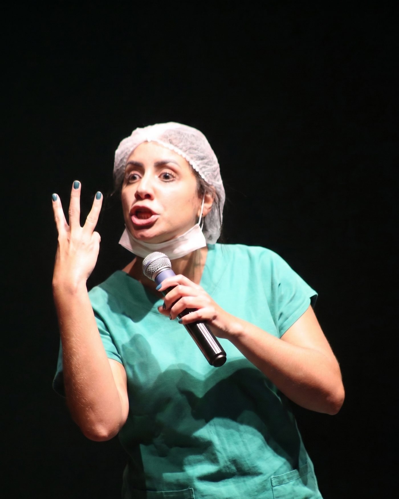 Camila Cardoso no palco, de touca e microfone na mão, durante o show