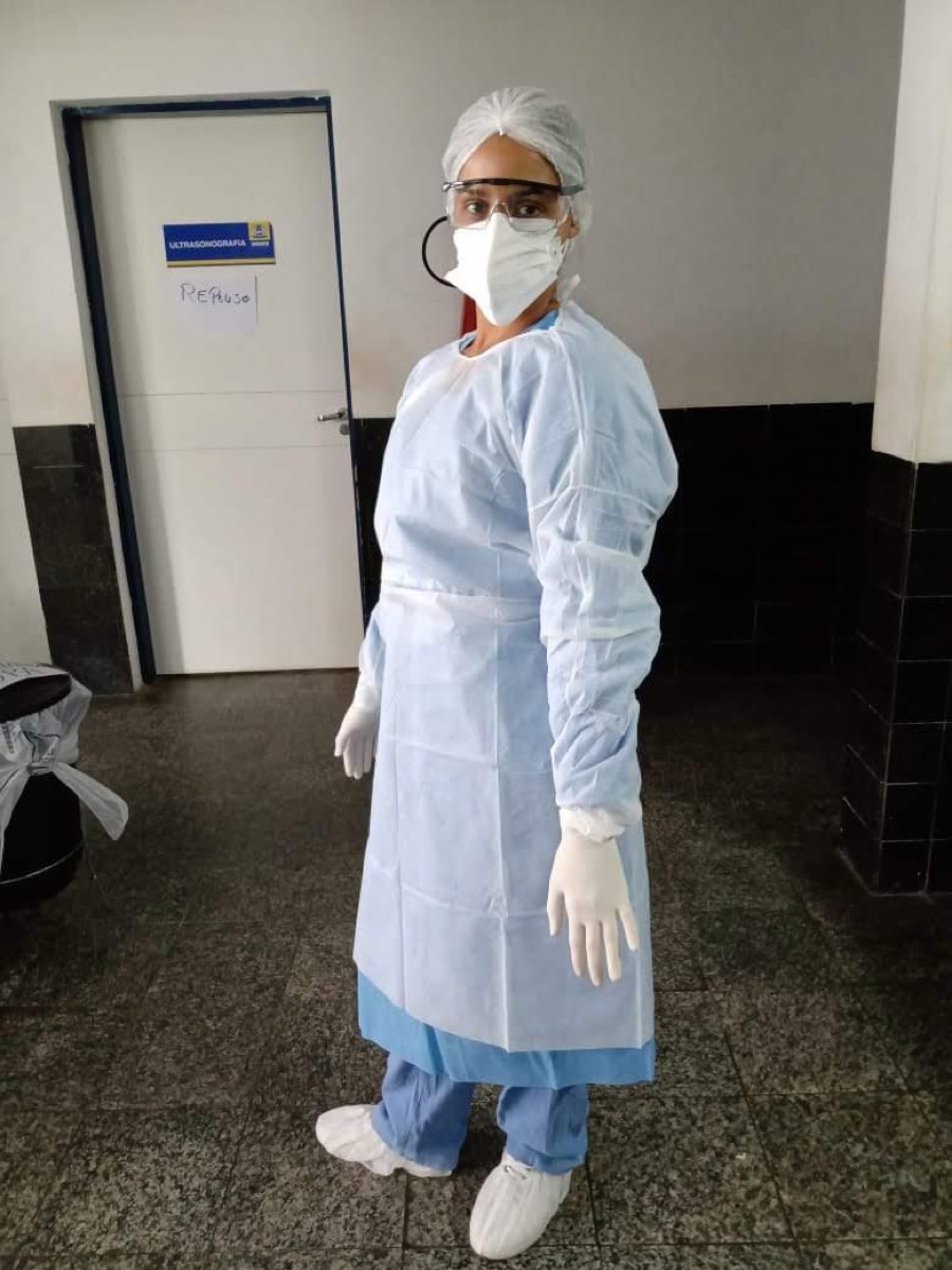 Camila Cardoso paramentada com EPI completo no corredor do hospital